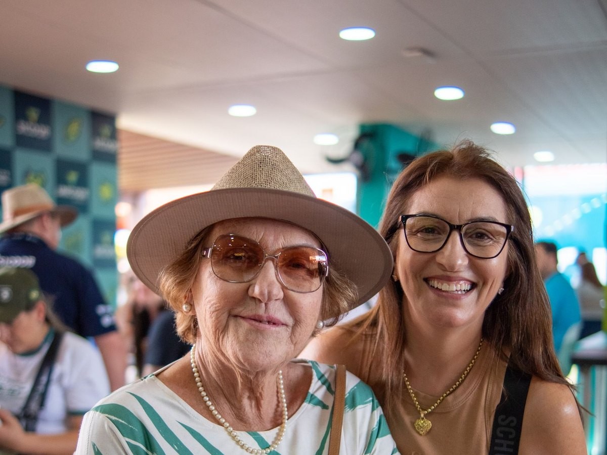 Senhora sorrindo abraçada à acompanhante