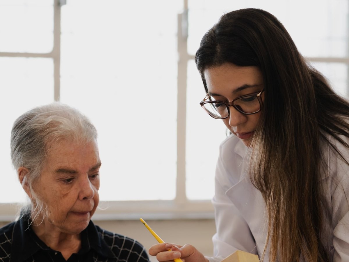 Acompanhante ajudando uma pessoa idosa à mesa