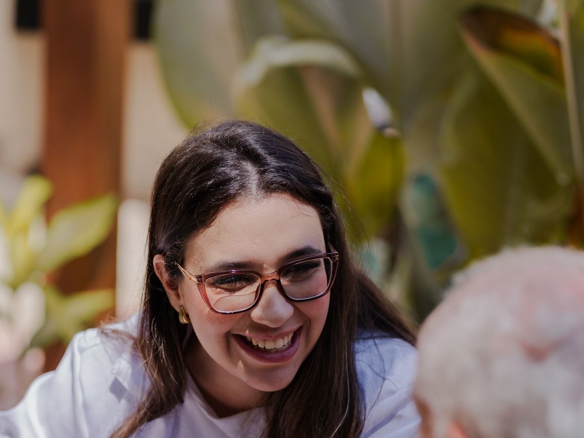 Acompanhante sorrindo ao lado de uma pessoa idosa